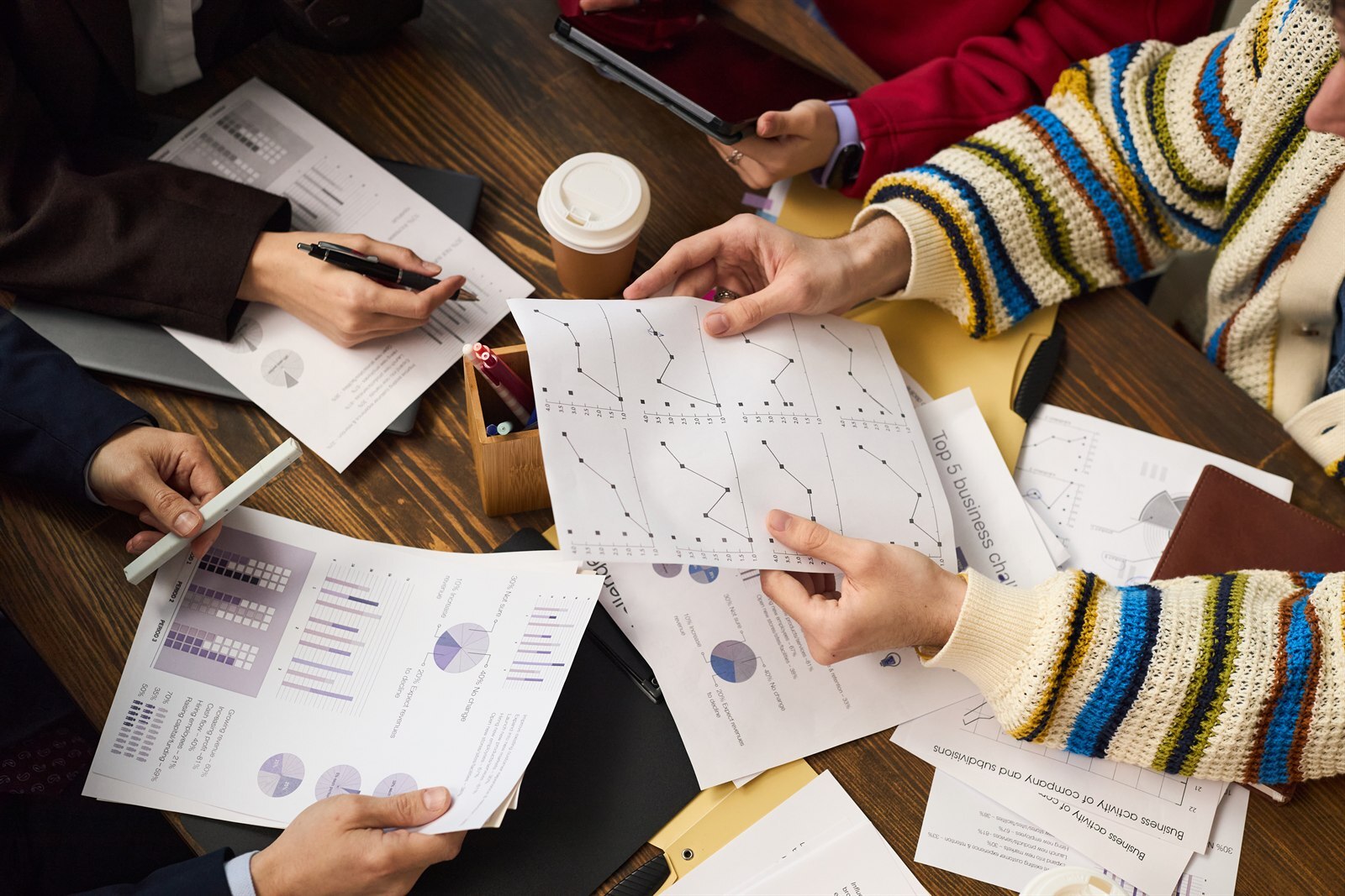 Colleagues reviewing printed performance data and charts around a meeting table