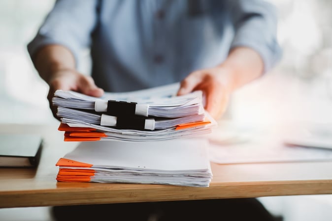 Finance professional working through a stack of charity due diligence files