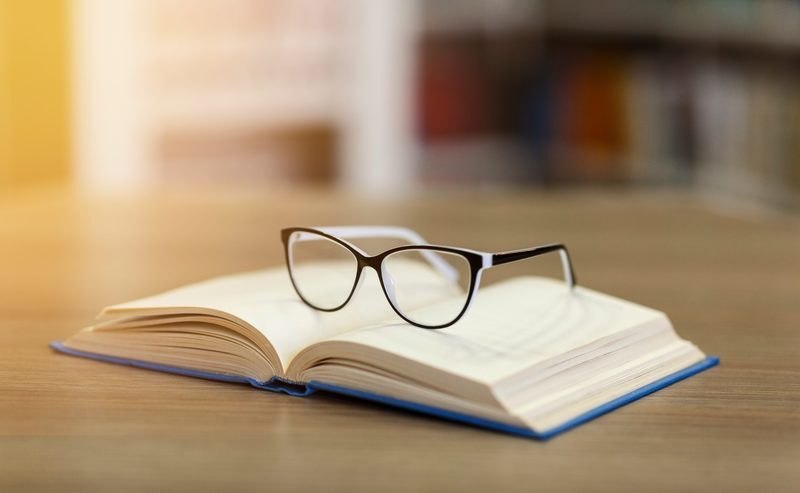 An open book and reading glasses in warm light
