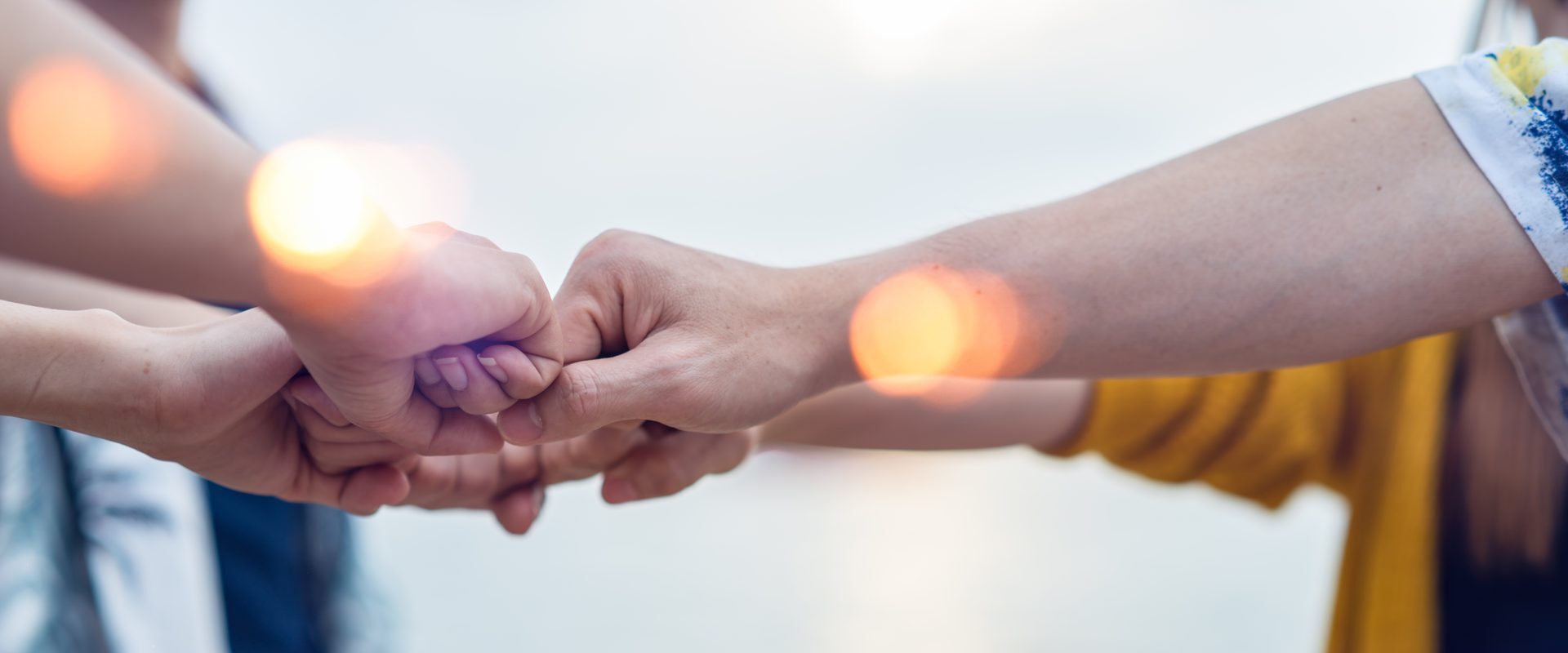 A stack of hands from a diverse group, joined in partnership