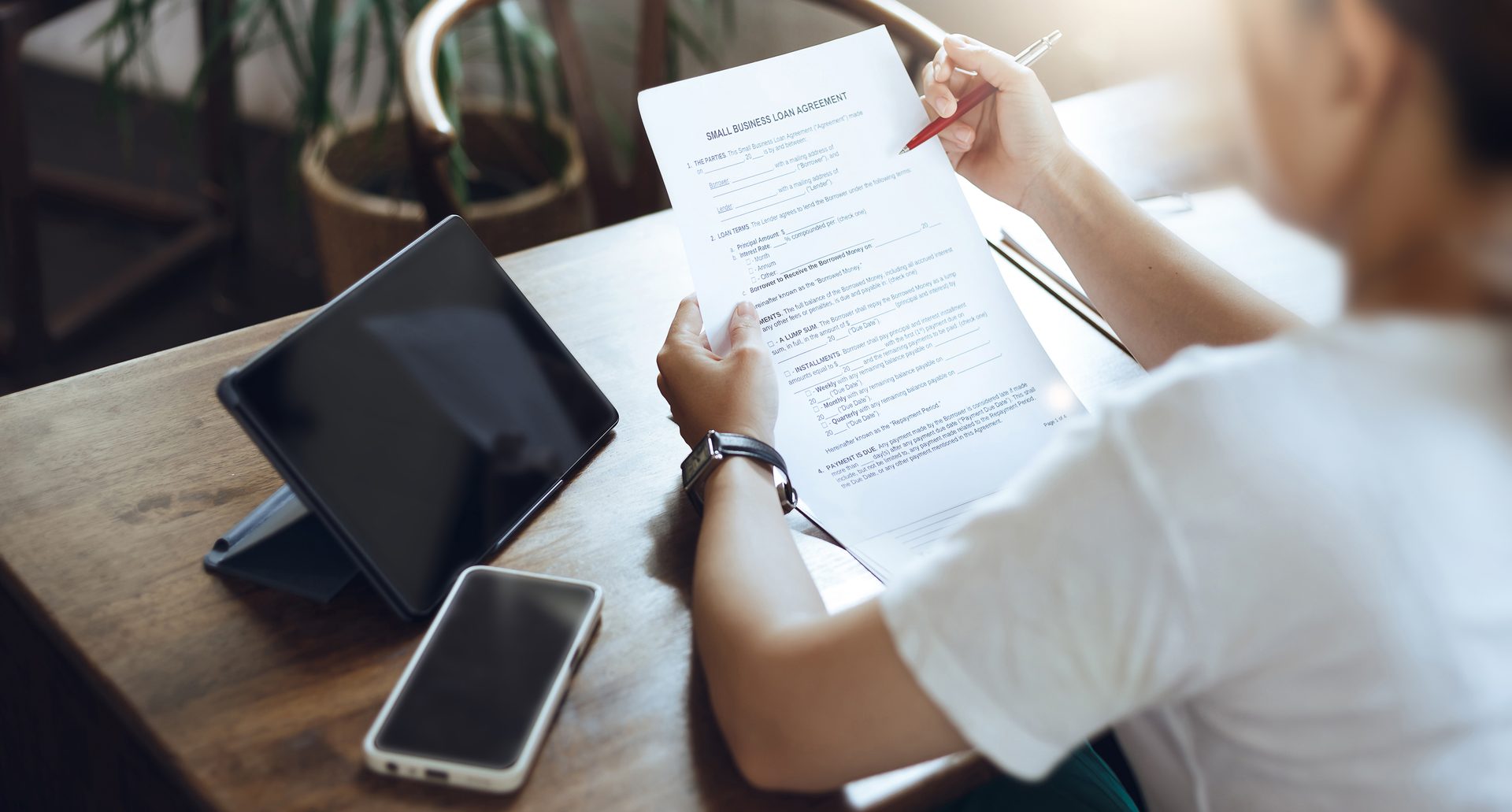 A woman reading funding documents at a desk with a tablet
